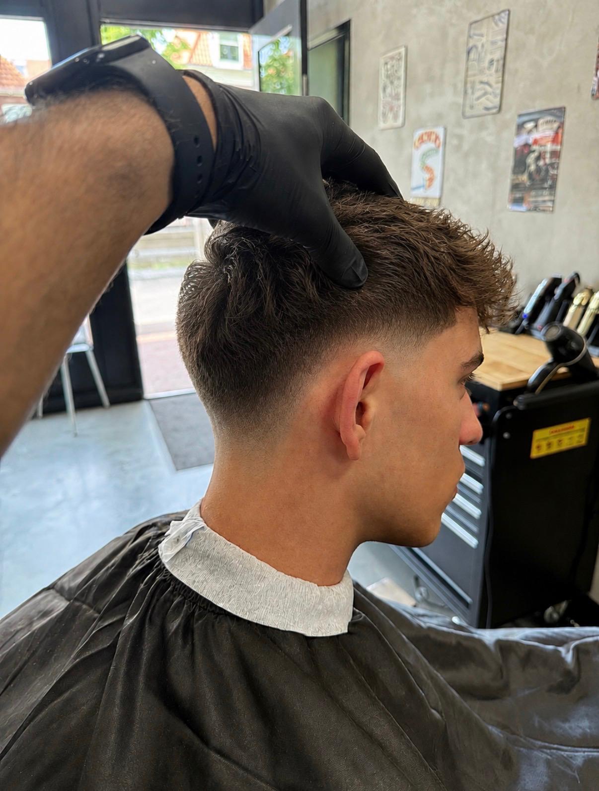 Getextureerd herenkapsel met een strakke low fade tijdens de afwerking bij Berkay's Barbershop in Hoorn
