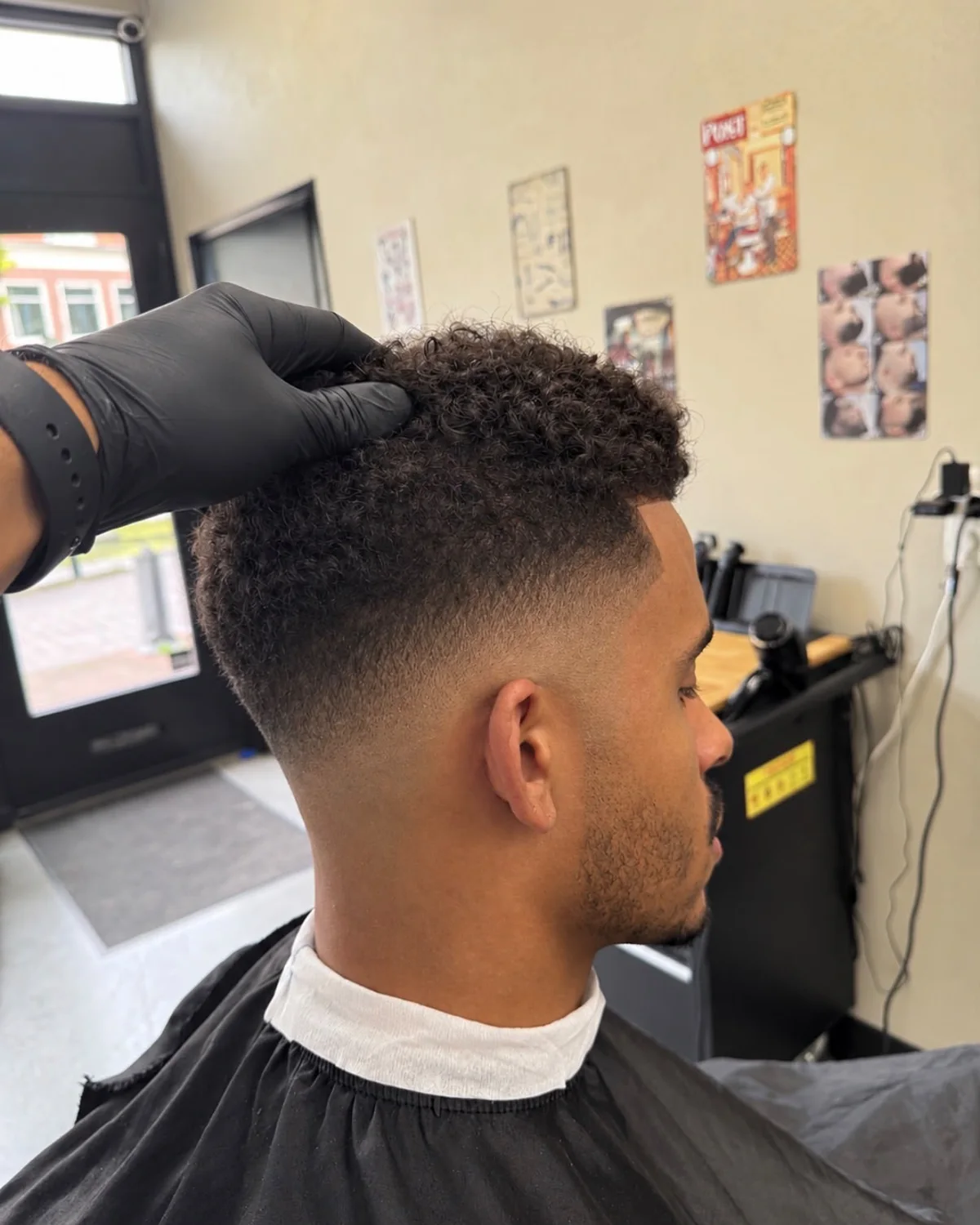 Krullend herenkapsel met een verzorgde low fade en korte baard bij Berkay's Barbershop in Hoorn