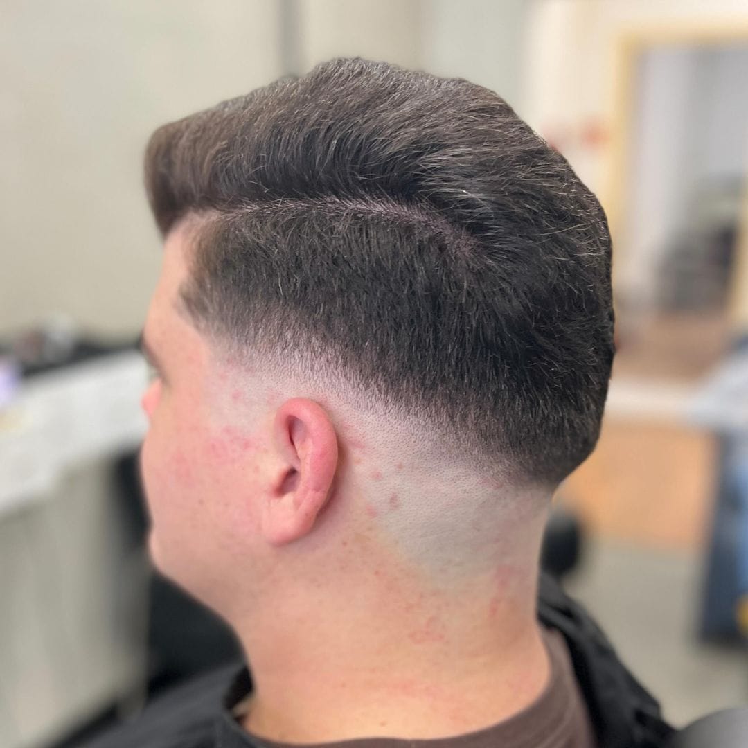 Donker getextureerd kapsel met low skin fade gezien vanaf de achterkant