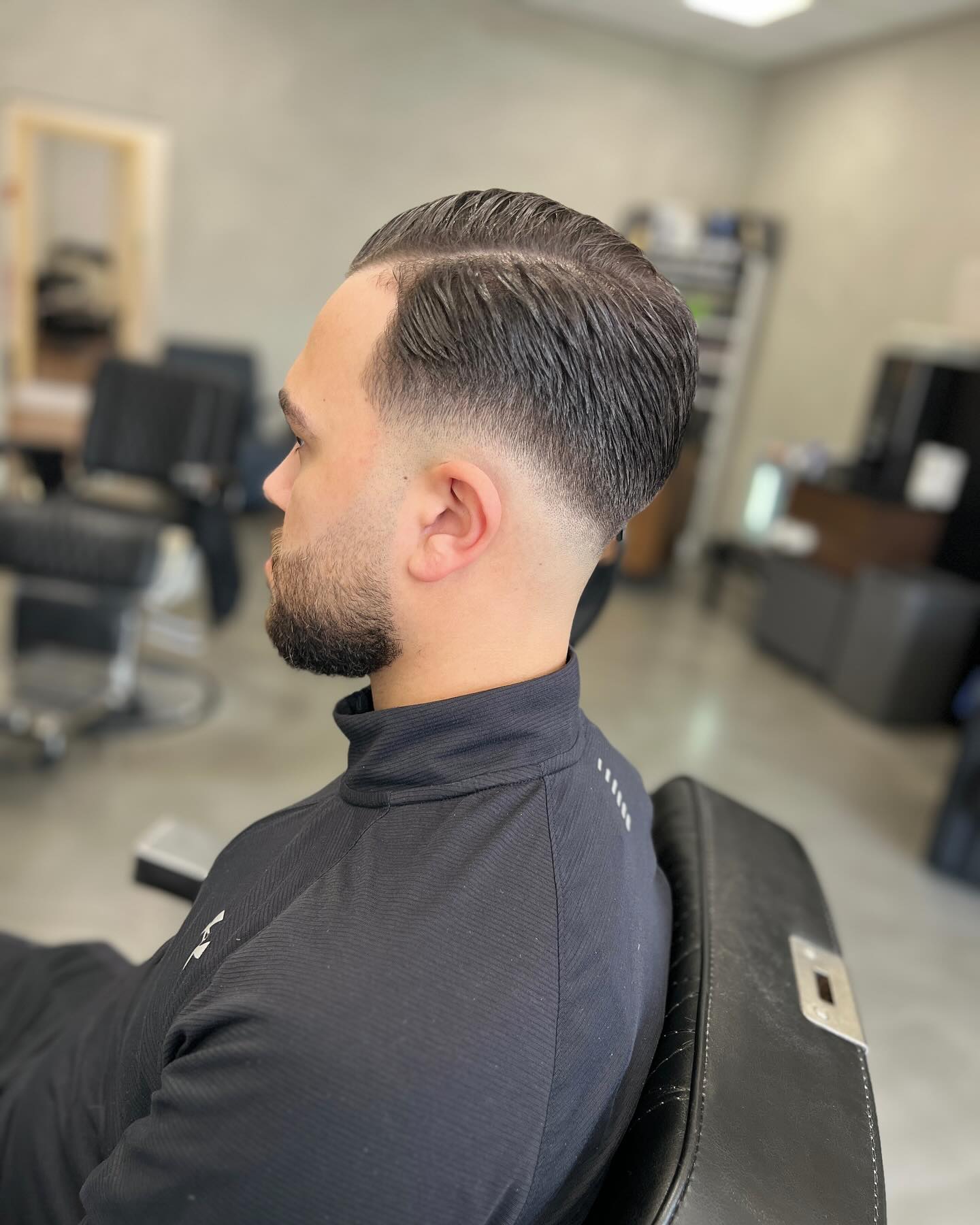 Achterovergekamd donker haar met mid fade en kort getrimde baard