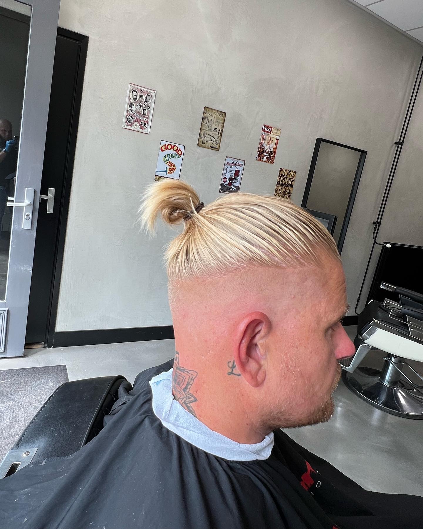 Platinablonde man bun met high skin fade en strak geschoren zijkanten