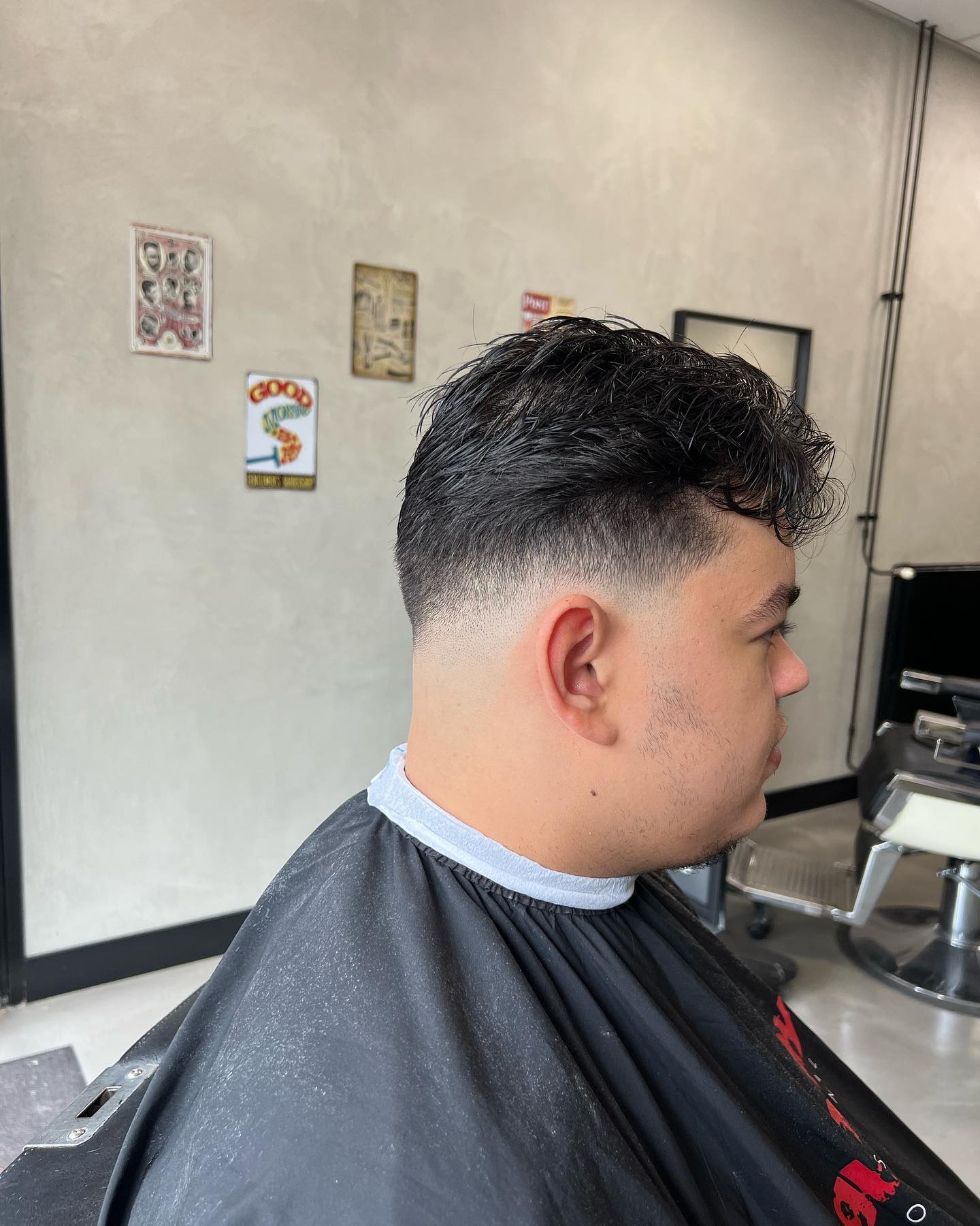 Dik golvend zwart haar met een strakke high fade aan de zijkanten