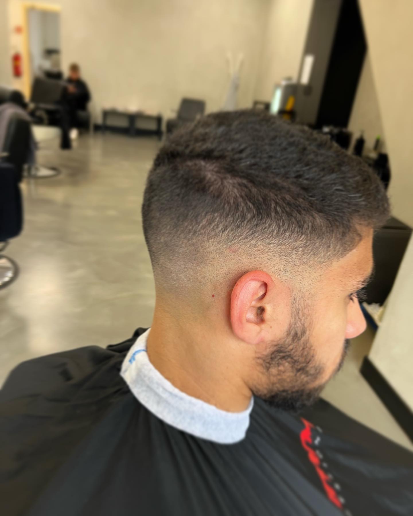 Kort krullend kapsel met mid skin fade en verzorgde korte baard