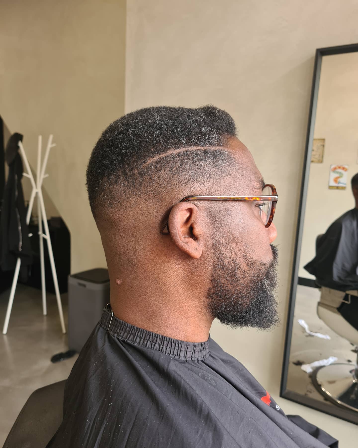 Kort afro fade-kapsel met baard en bril, strak afgewerkt in Hoorn