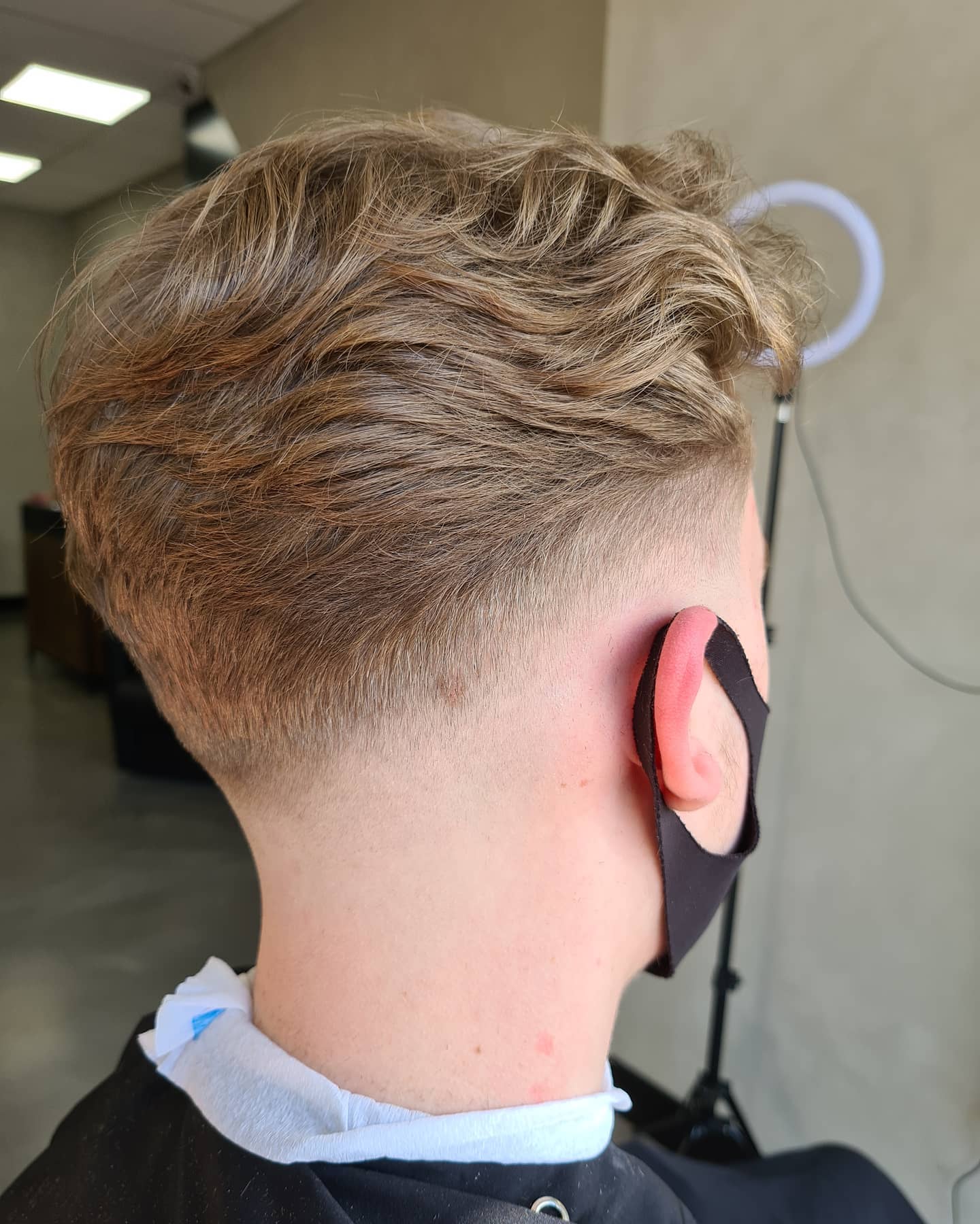 Blond getextureerd herenkapsel met een zachte fade in de nek