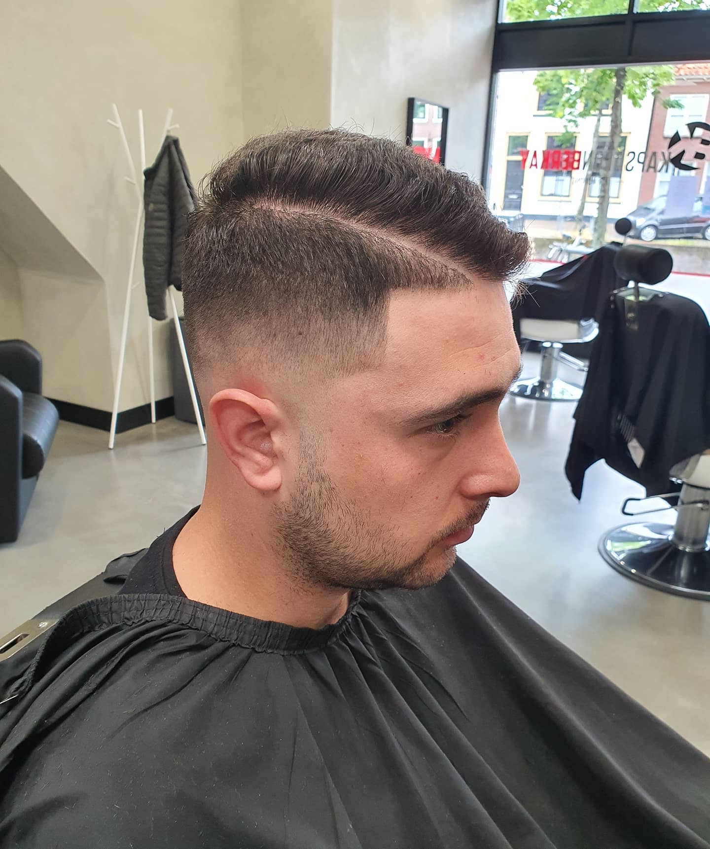 Getextureerde kuif met high skin fade en strak afgewerkte contouren