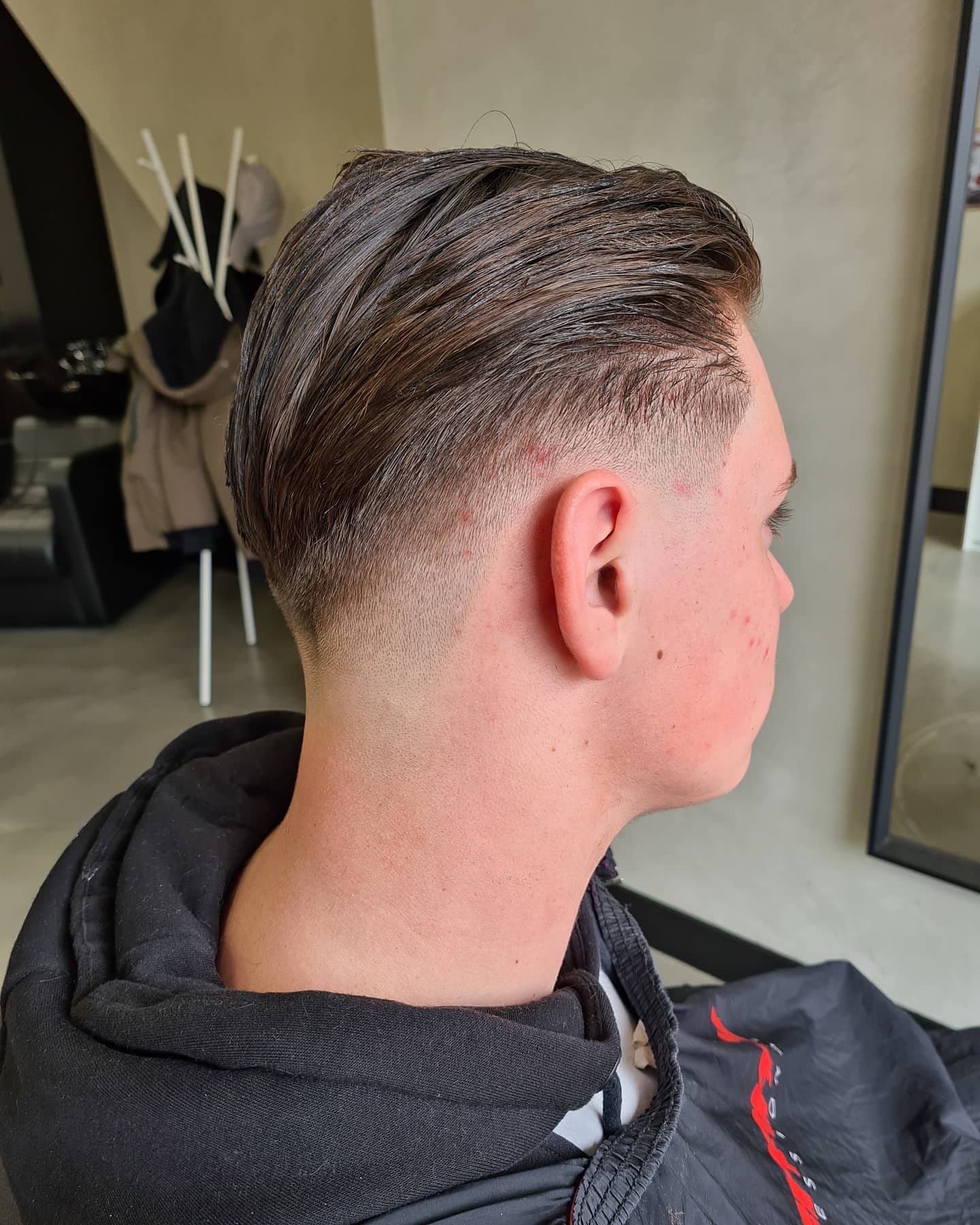 Lang donker haar achterover gestyled met kort opgeschoren zijkanten