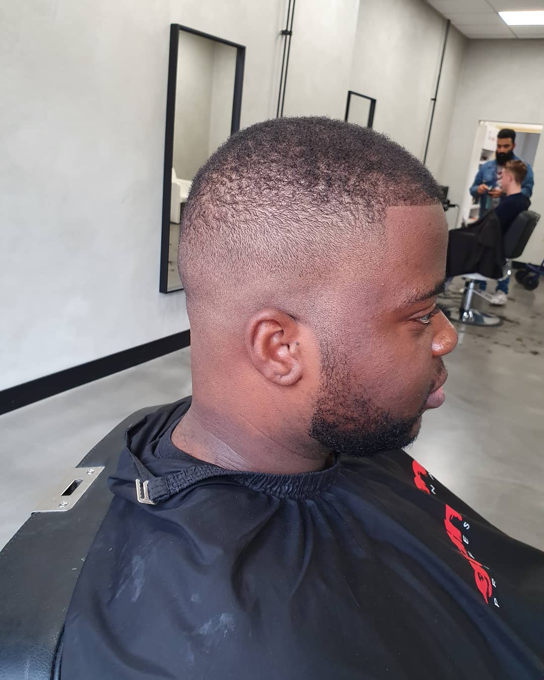 Kort afro-kapsel met high skin fade en strak gevormde baard