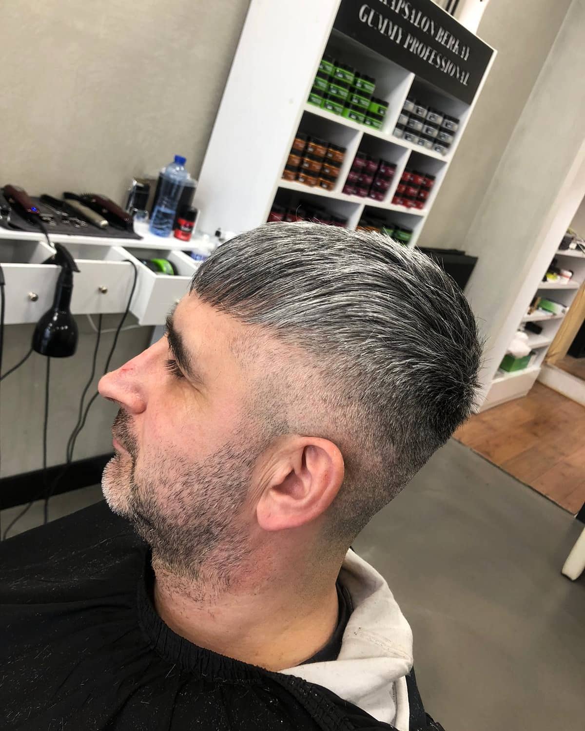 Zilvergrijs achterovergekamd kapsel met low fade en volle baard