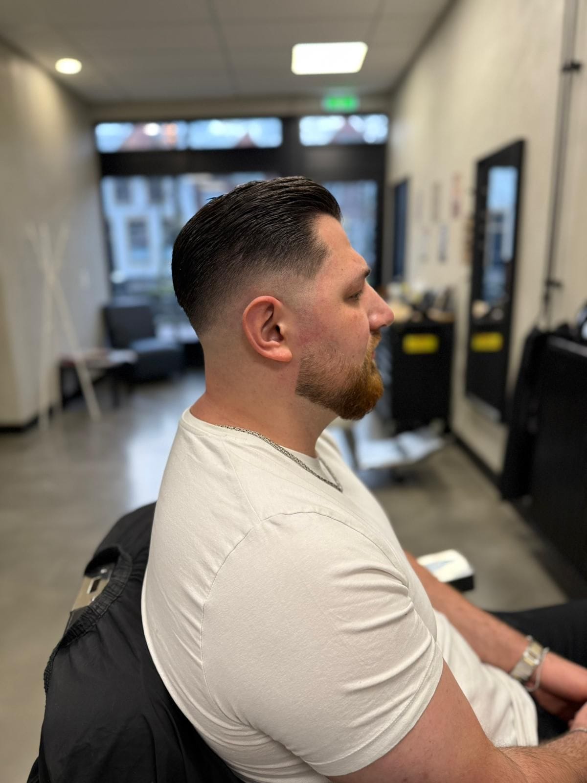Donker pompadourkapsel met low skin fade en verzorgde korte baard