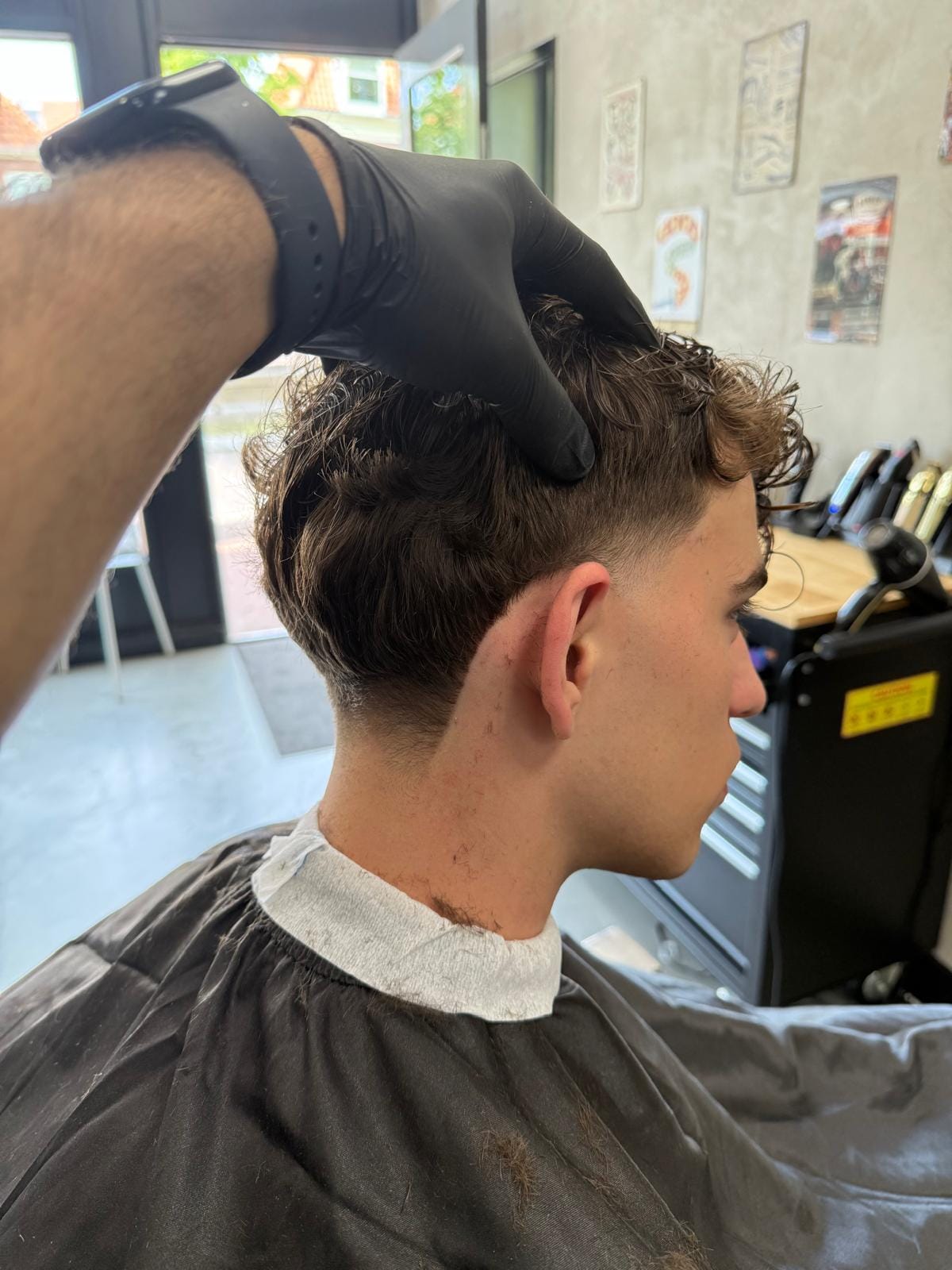 Barber knipt een getextureerd bruin herenkapsel met een strakke fade bij Berkays Barbershop in Hoorn
